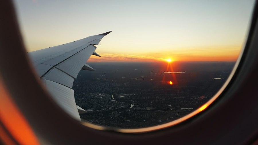 Sunset over an aircraft wing seen from the cabin window